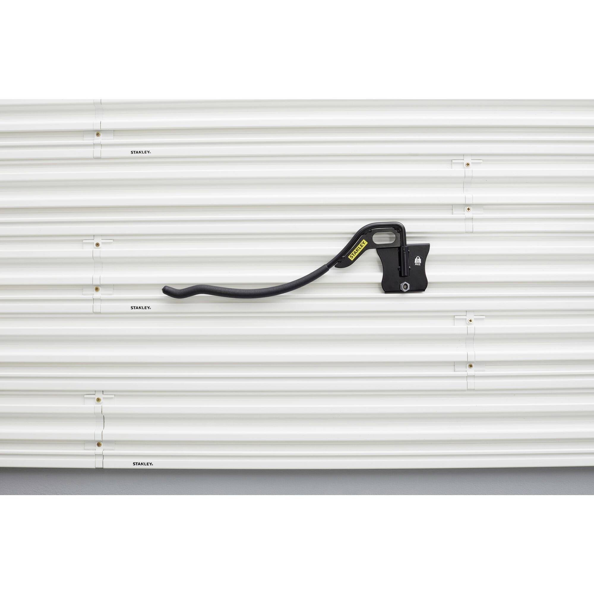A white corrugated metal wall with a black bicycle mount attached.