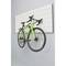 A green bicycle is suspended vertically on a white ribbed wall mount in a modern room.