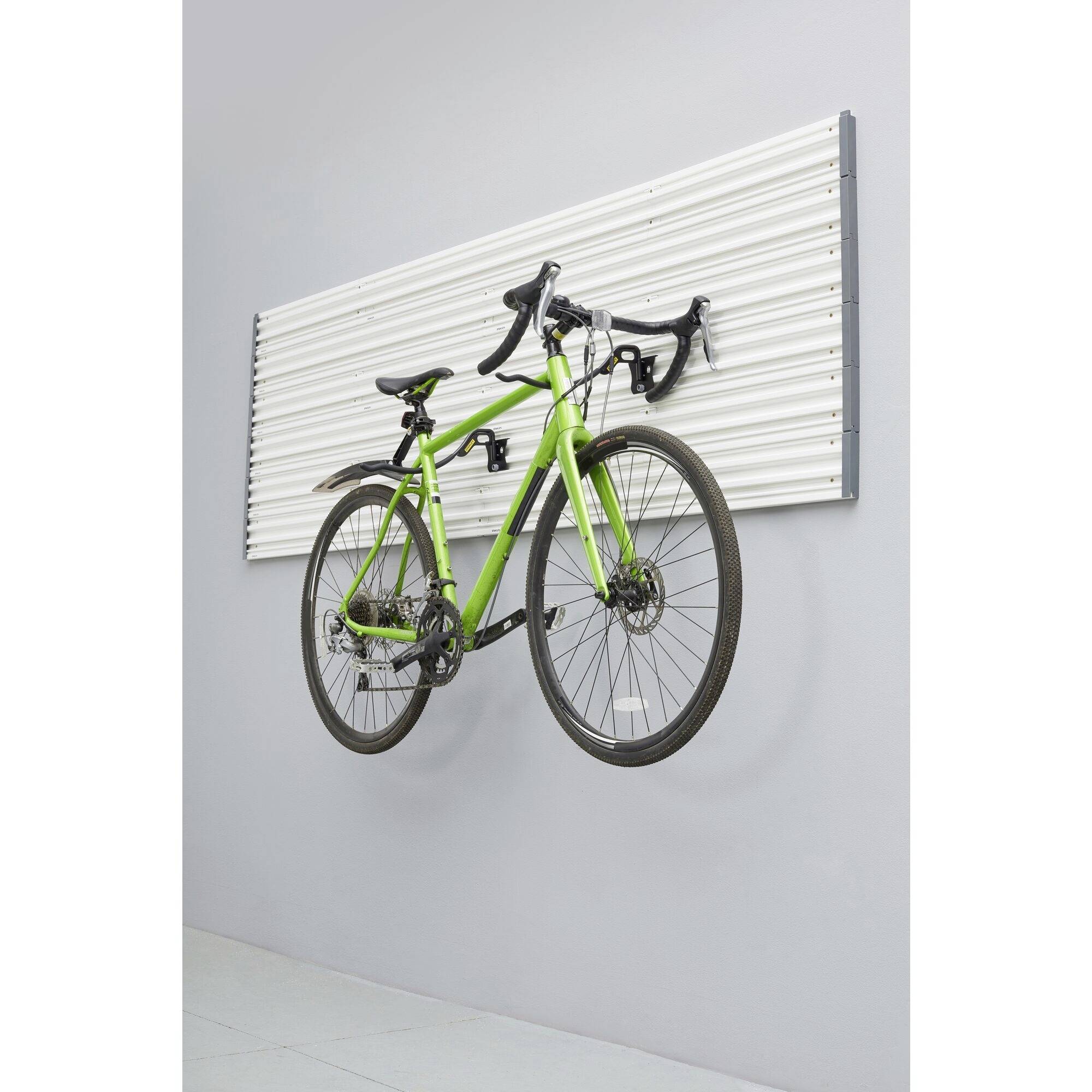 A green bicycle hangs on a wall mount in a minimally furnished room.