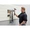 A man is hanging a hammer on a wall bracket that organises various tools, including screwdrivers and a saw.