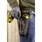 A person is wearing a Stanley tool belt with screwdrivers and a yellow cordless drill in a wood-panelled room.
