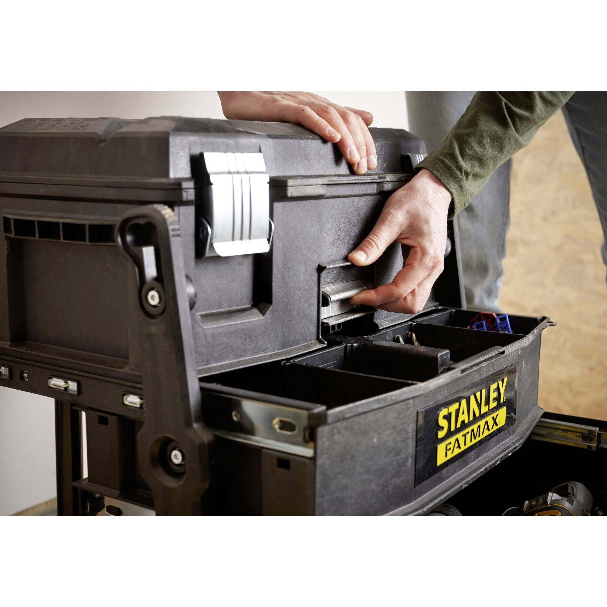 A person pulls out a drawer from a black STANLEY FATMAX toolbox. Hands are interacting with the equipment.