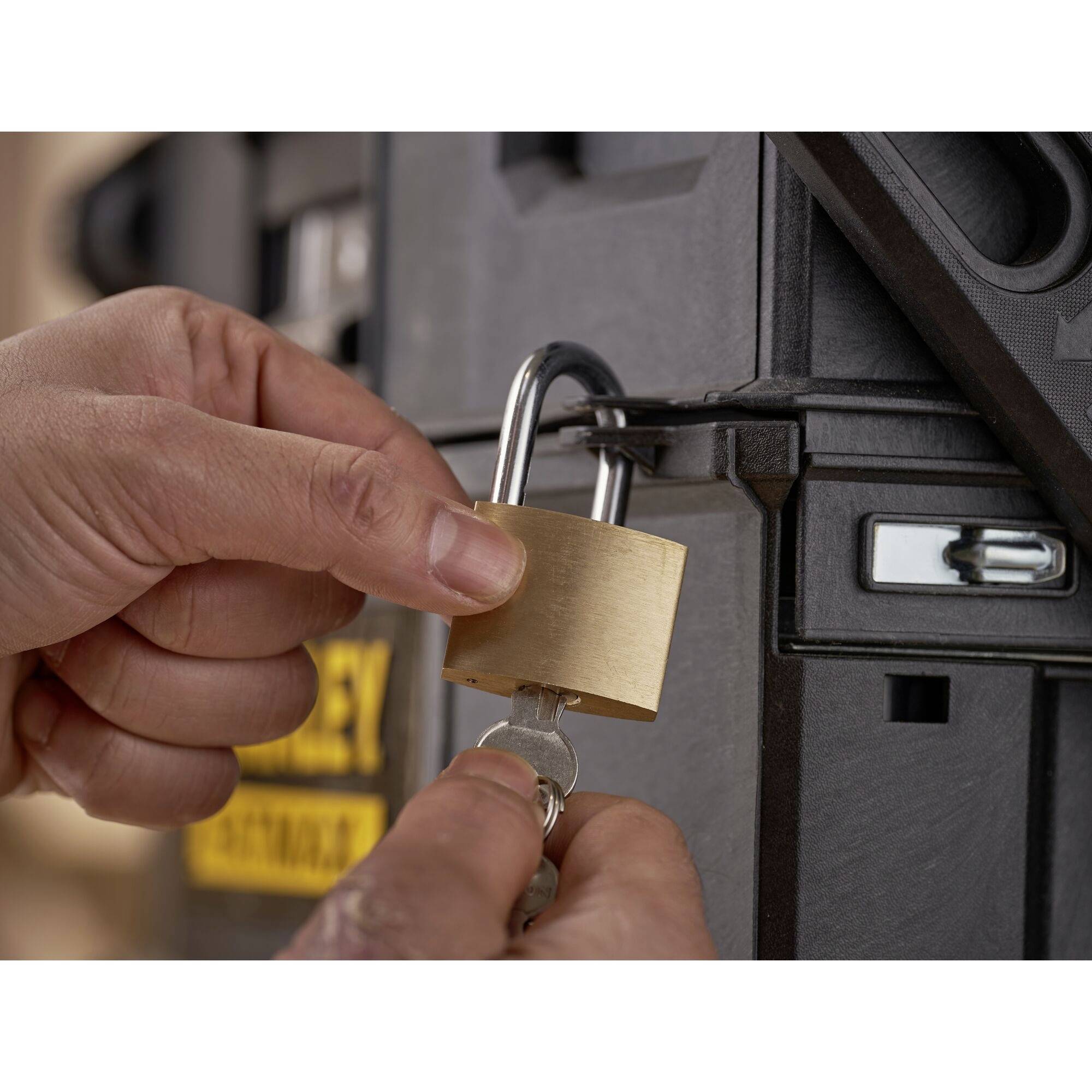 A hand turns a key in a brass lock on a black box, symbolising security or protection.
