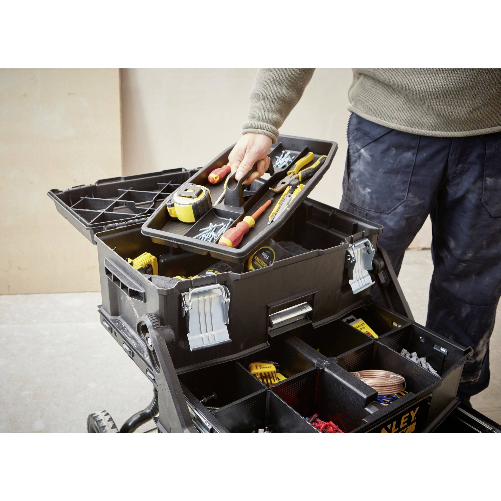 A person is organising tools in a large, open toolbox with multiple compartments. Screwdrivers and pliers are visible.