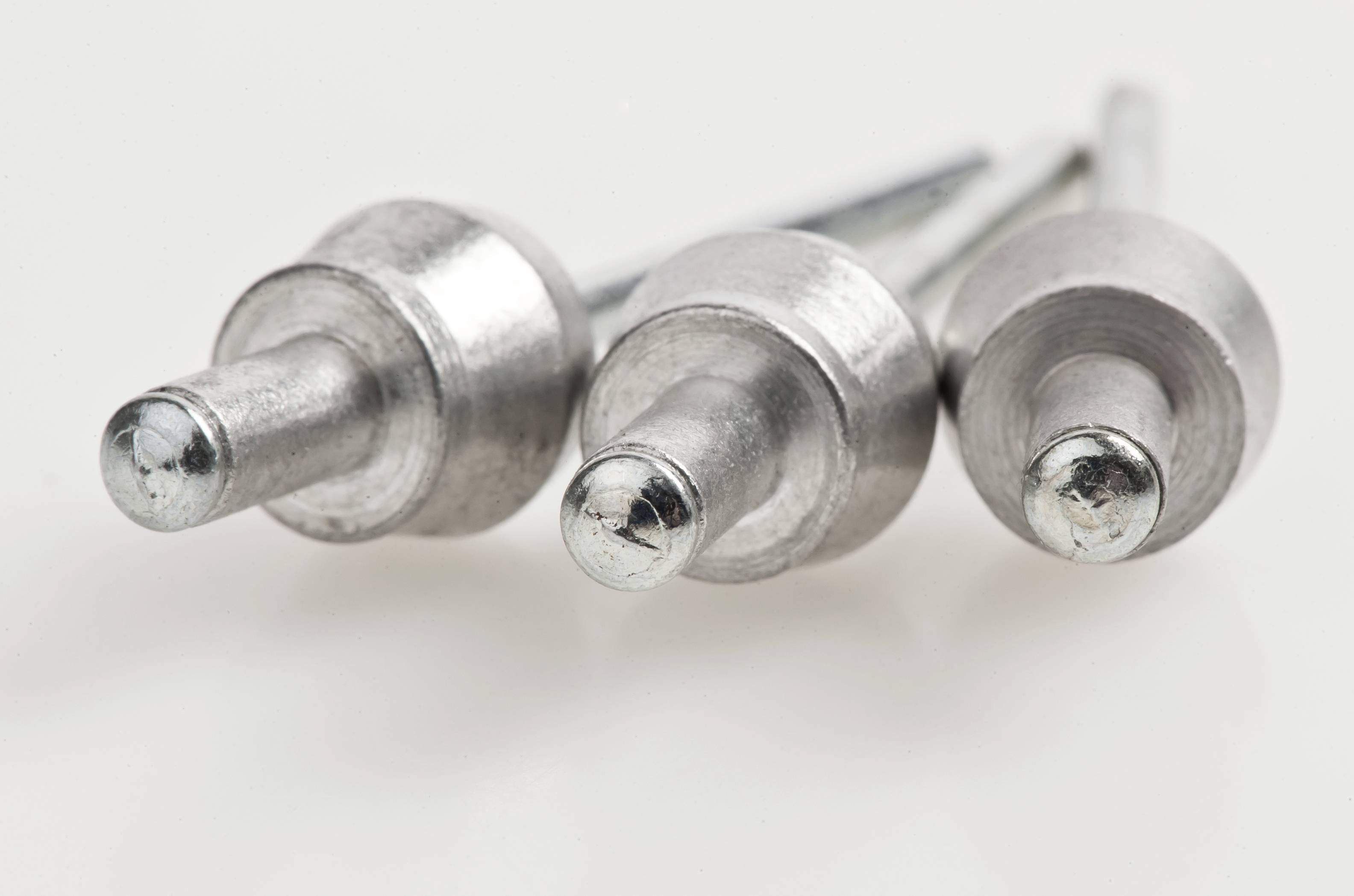 Three silver rivets are positioned side by side on a white background.
