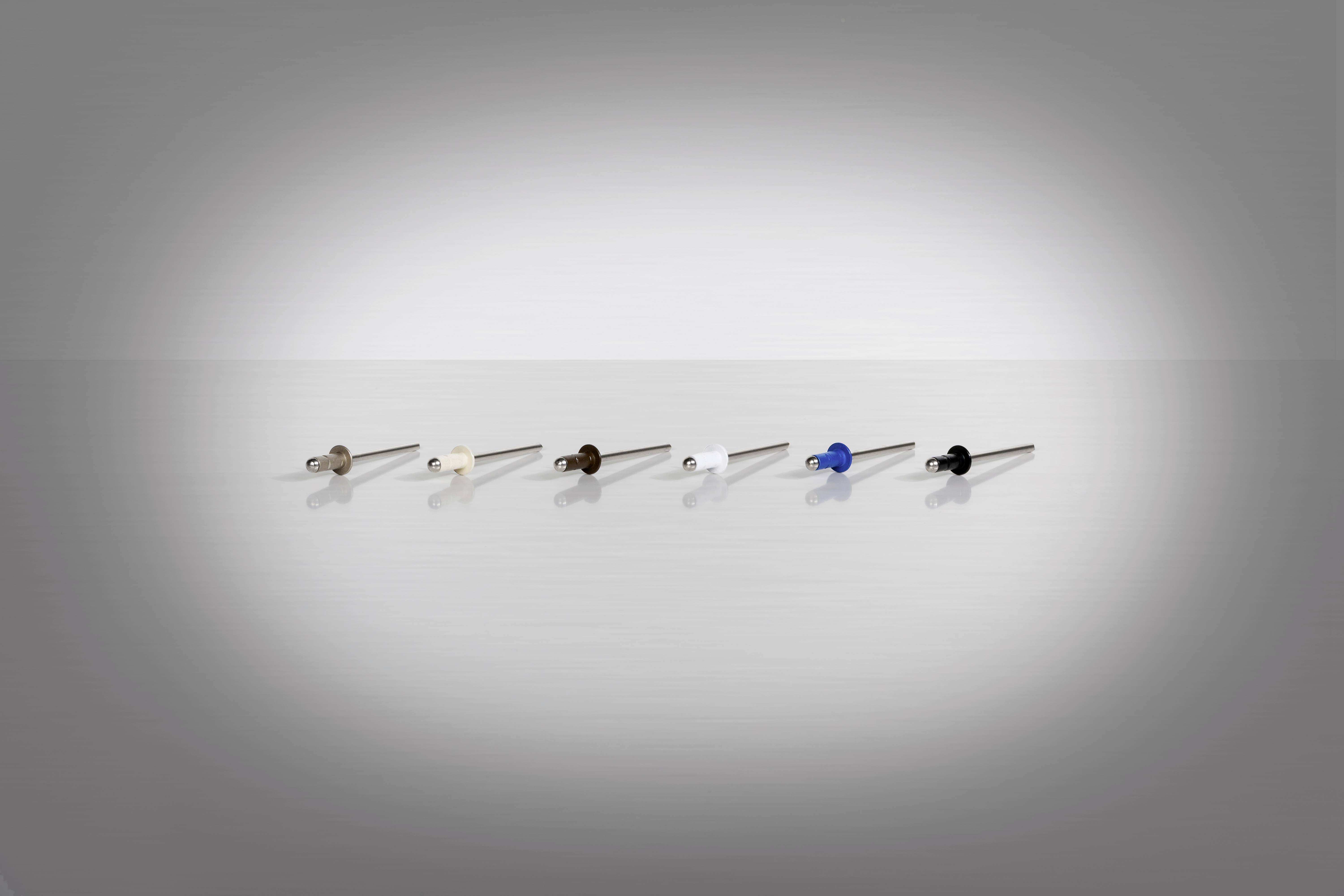 Six differently coloured rivets arranged in a row on a glossy surface background.