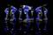 Four blue, battery-powered electric tools are reflected against a black background. They are lined up in a row and pointing forwards.