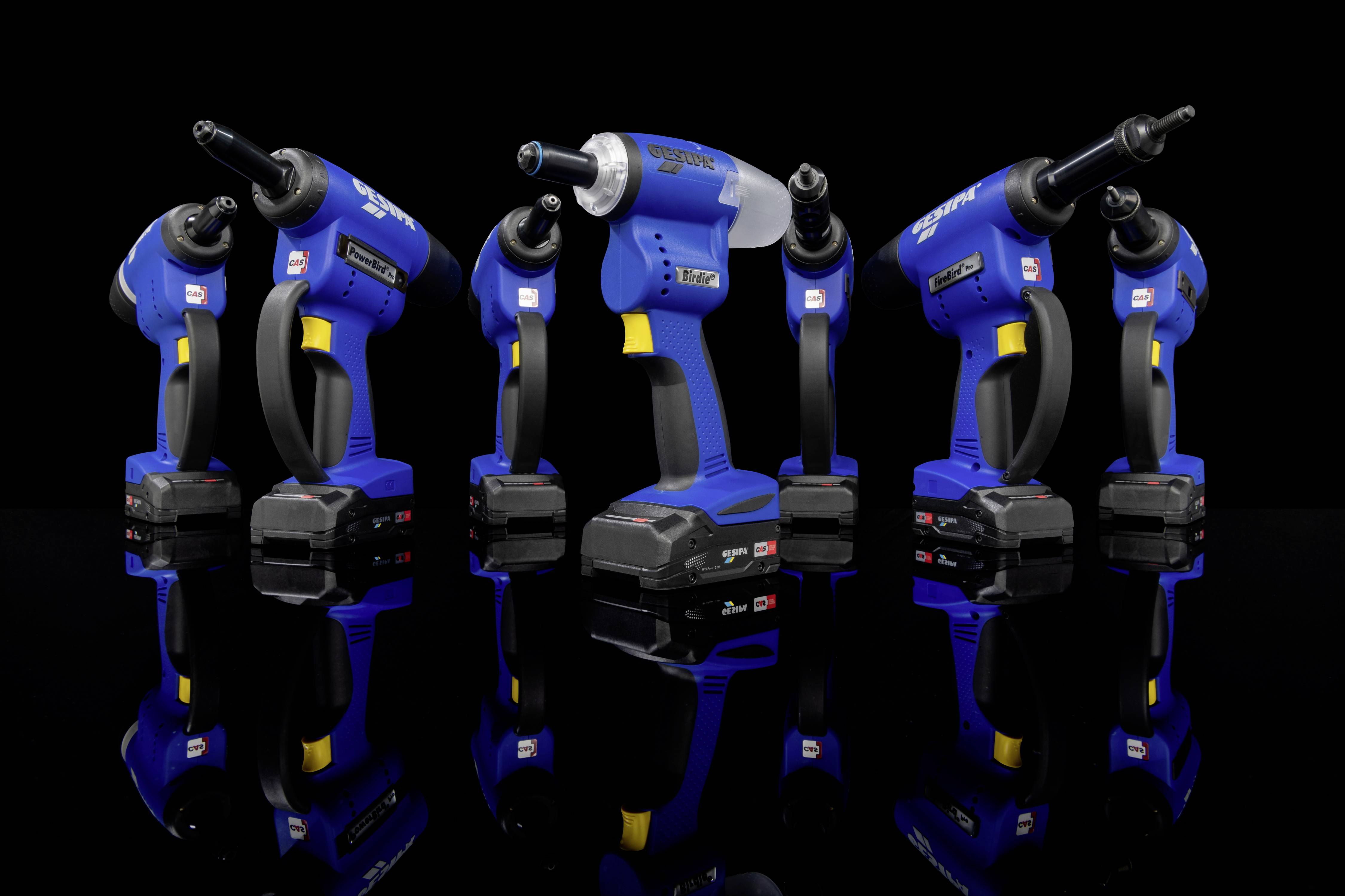 Five blue, cordless power tools stand upright in a row on a black, reflective surface.