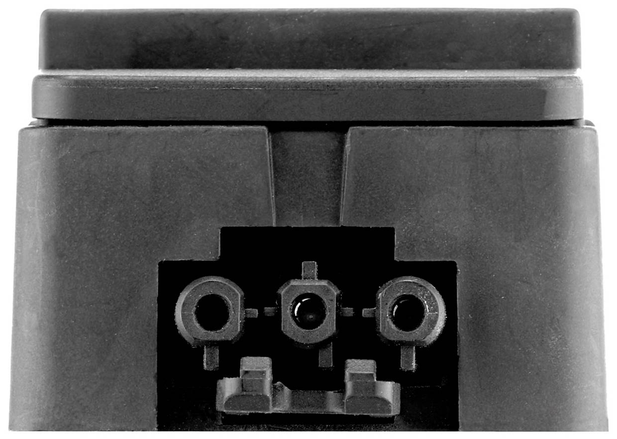 Black and white close-up of an electrical connector with three round sockets in the centre.
