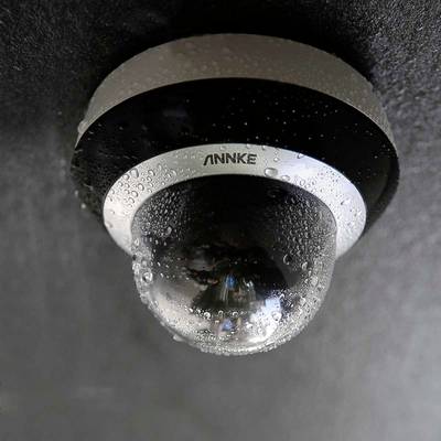 Surveillance camera on a wall, covered in water droplets.