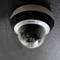 Surveillance camera on a wall, covered in water droplets.