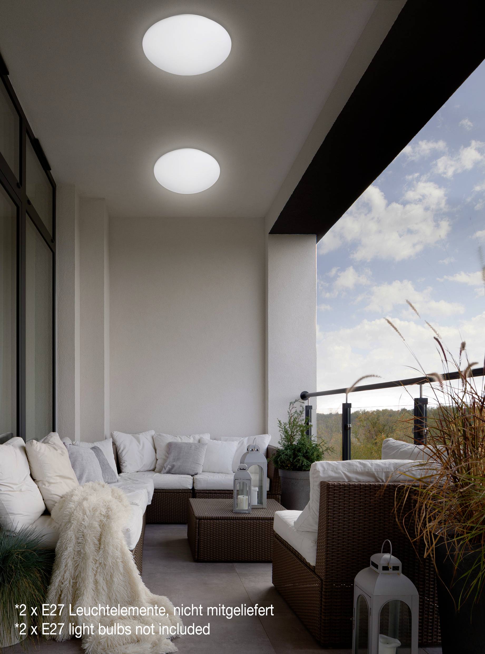 A balcony with a cosy seating area, decorated with plants. Two round ceiling lights hang above the sofa.