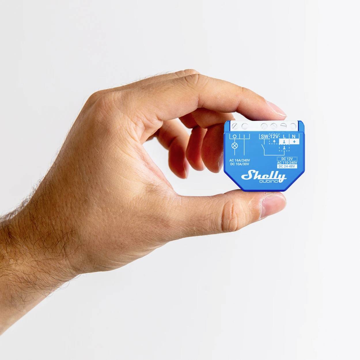 A hand is holding a blue technical device with various symbols and text on it, potentially a smart home module.