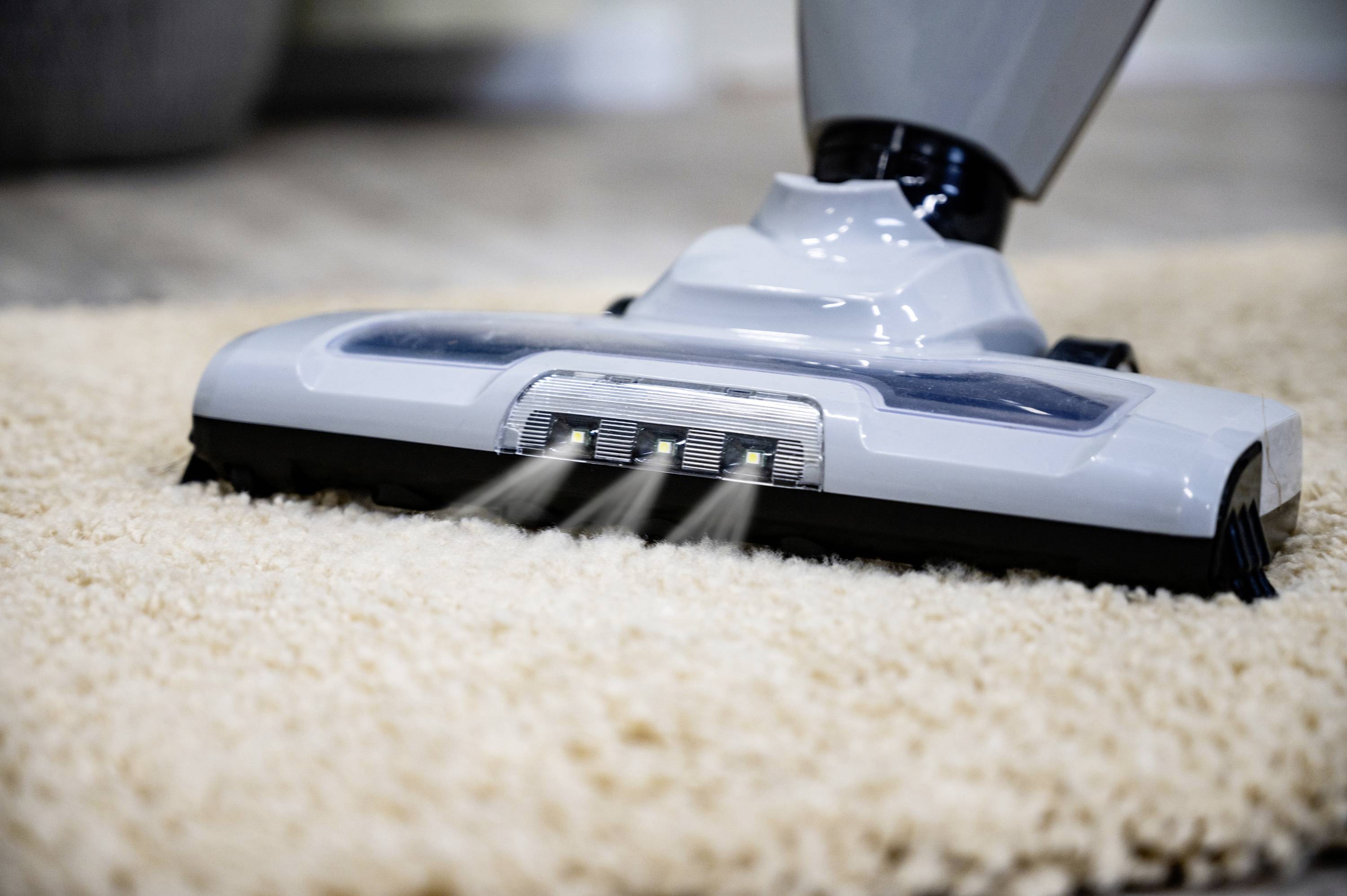 Vacuum cleaner head cleaning beige carpet.