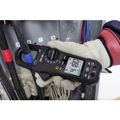 A gloved hand holds a digital multimeter measuring 48.0 amperes in front of an electrical distribution board.