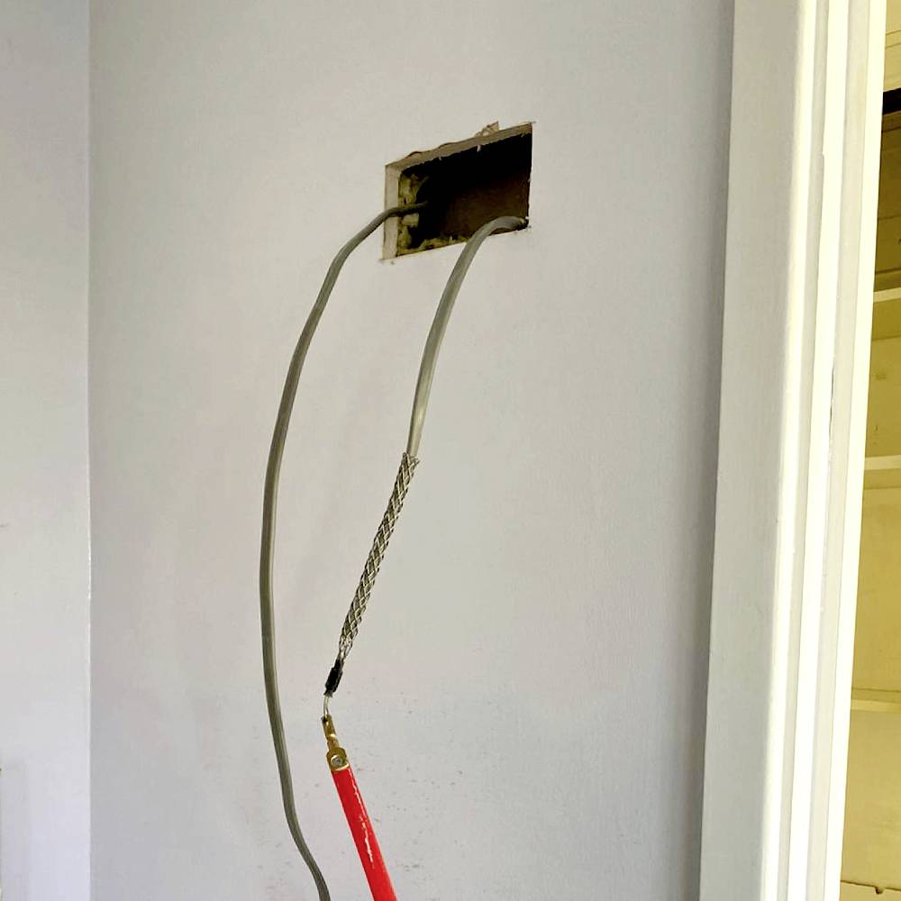 A socket in the wall with a protruding cable and appropriate tools. The surrounding area suggests ongoing electrical installation work.