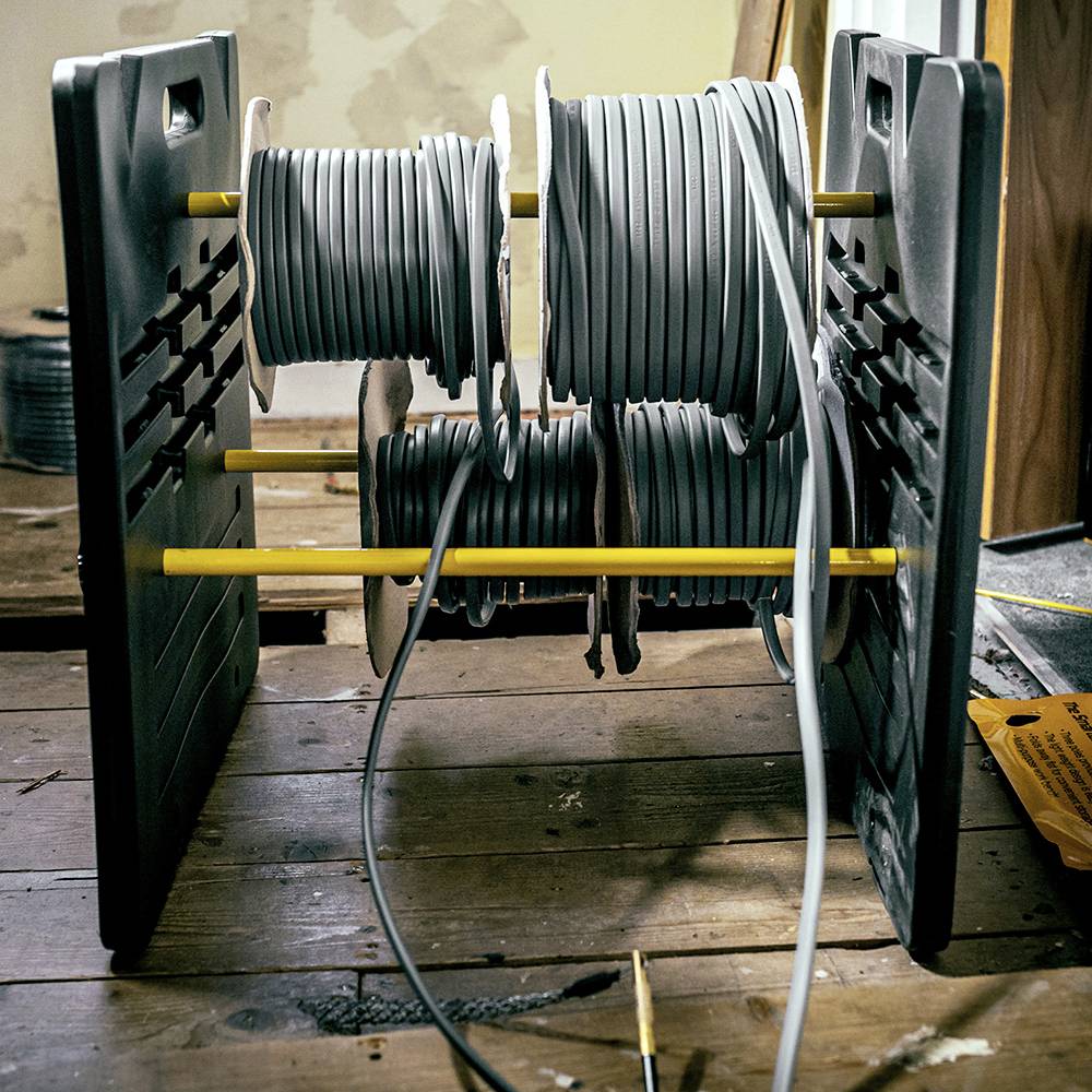 Spools of grey cables on a wooden stand, neatly arranged and ready for use in electrical or craft work.