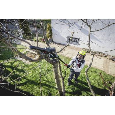A man is pruning branches from a tree with a pair of secateurs in a garden. He is wearing protective clothing and a helmet.