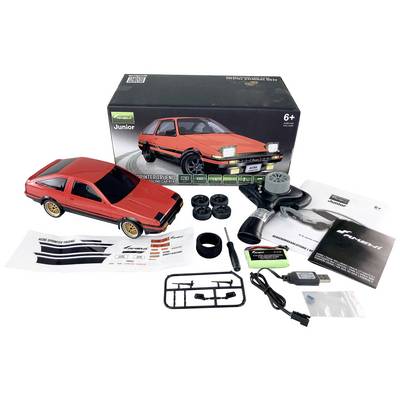 A red model car with accessories and instructions, ready for assembly. The packaging shows the completed car, suitable for ages 6 and up.