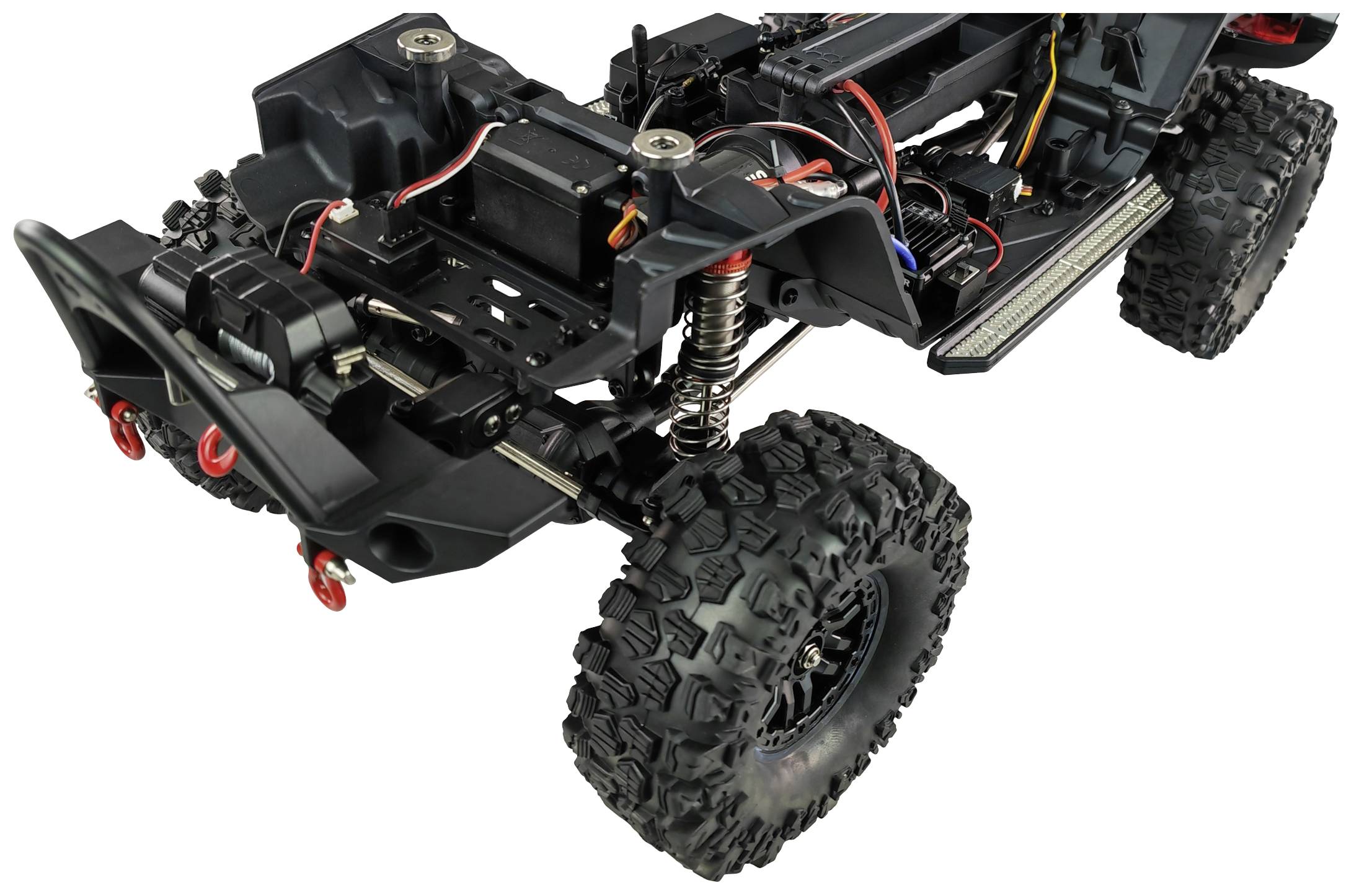 Close-up of a remote-controlled vehicle chassis without bodywork. Electronics, suspension, and off-road tyres are visible.