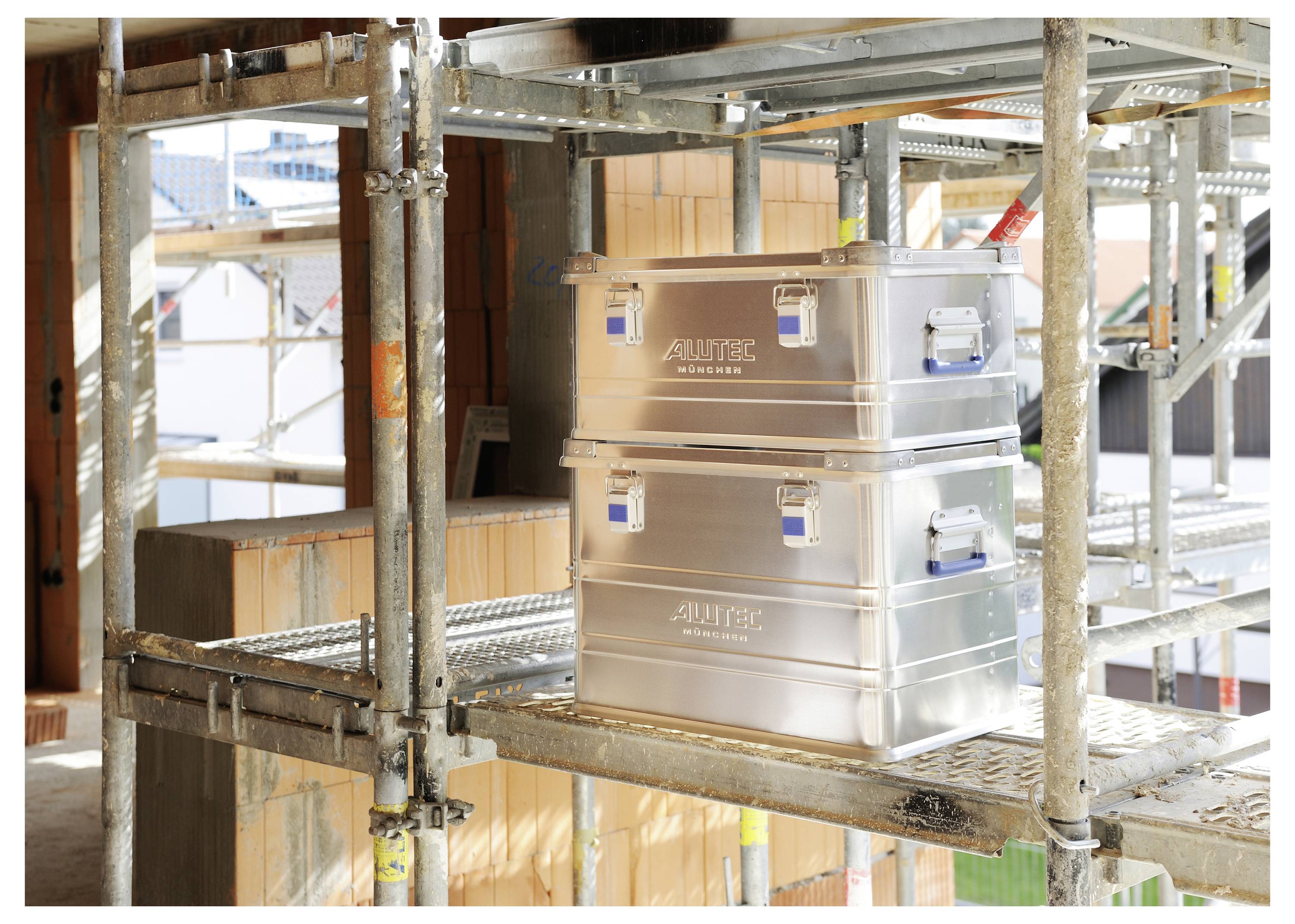 Steel boxes stacked on construction scaffolding with surrounding building materials and framework visible.