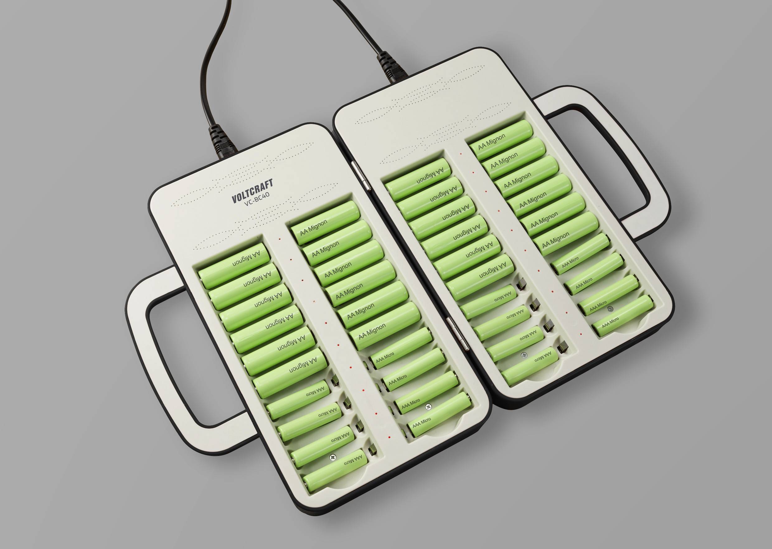 Batteries in a twin charger, several green rechargeable batteries being charged simultaneously. Each slot indicates a red or green charging status.