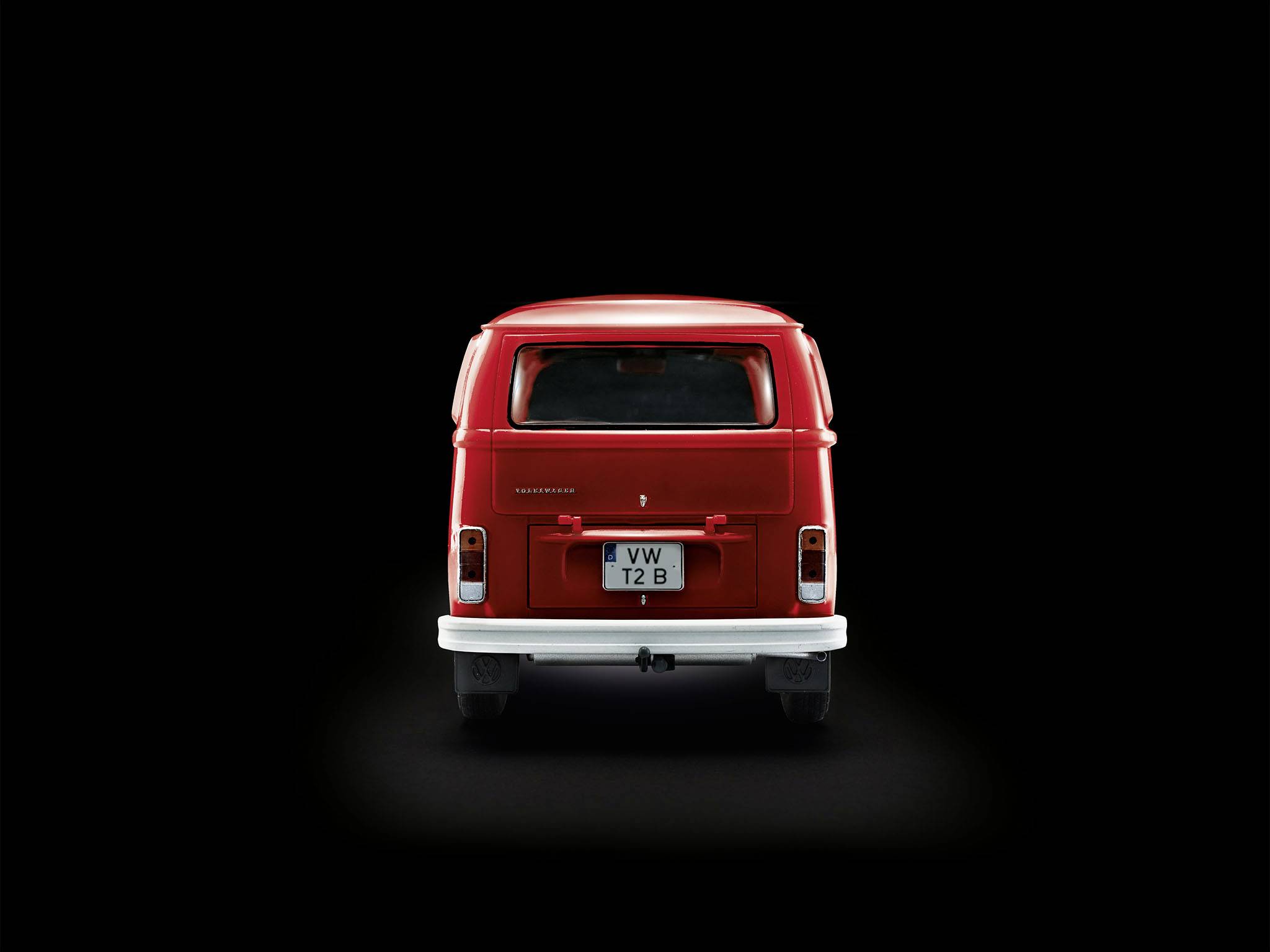 Red VW van from behind, in the foreground against a dark background.