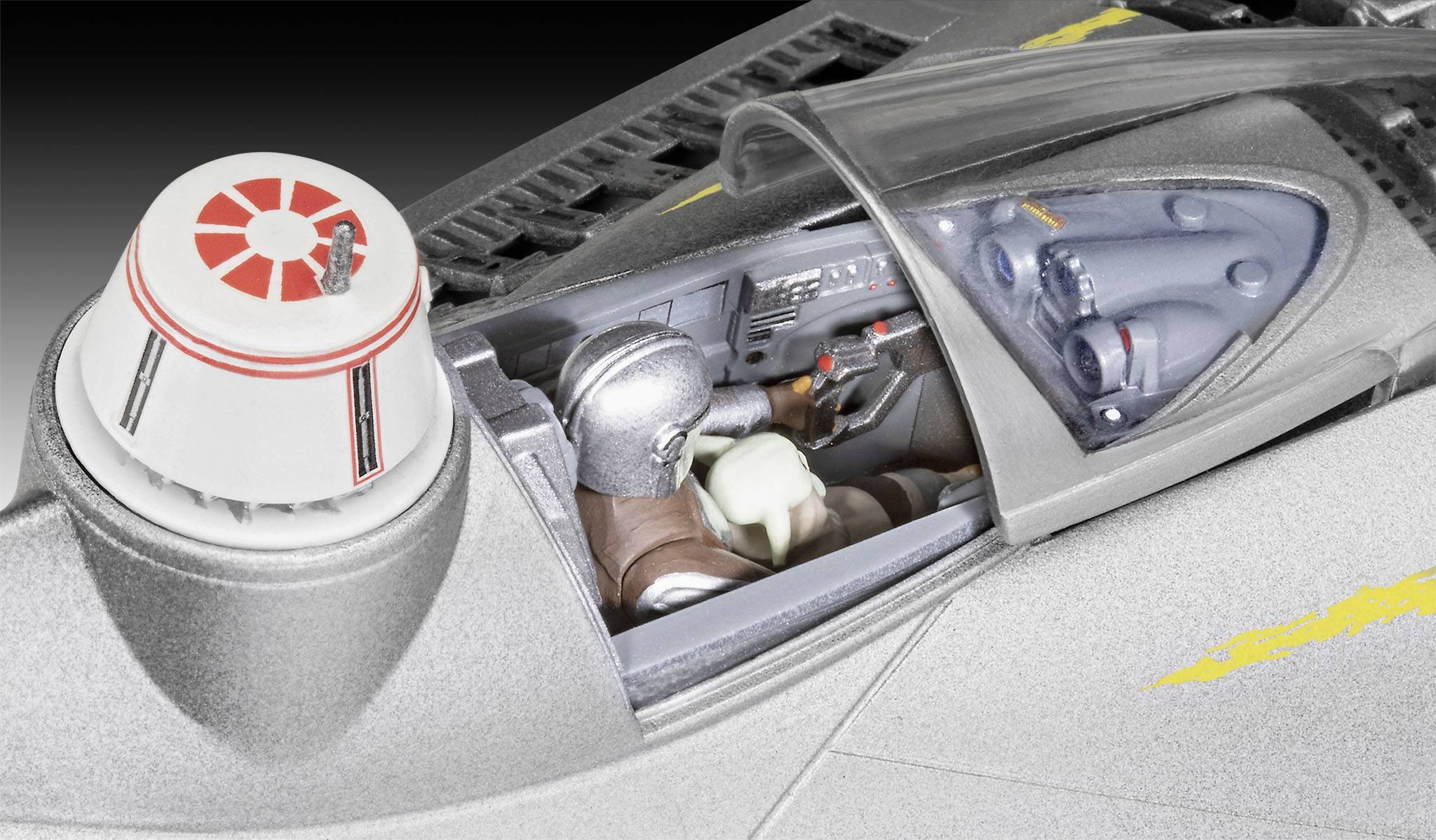 A silver spaceship model with a transparent cockpit. Inside, two figures in spacesuits can be seen.