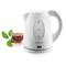 A white kettle beside a cup of tea with fresh green leaves.