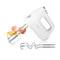 A white hand mixer with two whisks and two dough hooks is lying on a white surface. Three eggs are in the background.