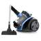 A blue, modern vacuum cleaner with a transparent dust container stands upright. To its right, the floor nozzle is visible.