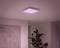 A square ceiling light emitting soft pink light illuminates a room ceiling. A plant stands beside it.