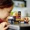 A child is happily playing with a LEGO set representing a burger truck, including a man with a hamburger.