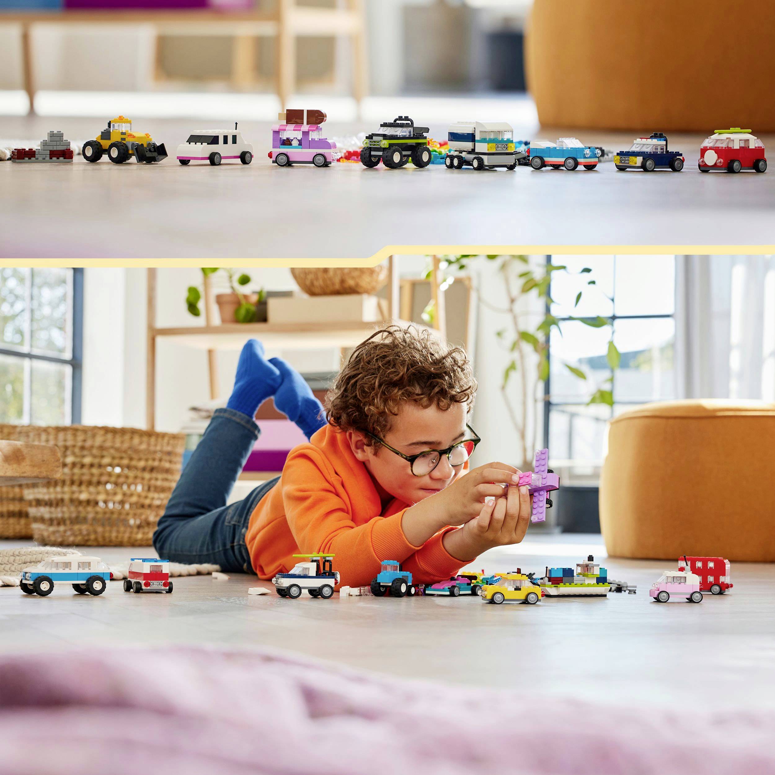 A child is lying on the floor playing with a set of small building block vehicles. Bright furniture can be seen in the background.