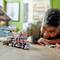 A child plays with a toy lorry and helicopter on the floor. In the background, furniture and decorations are blurred.