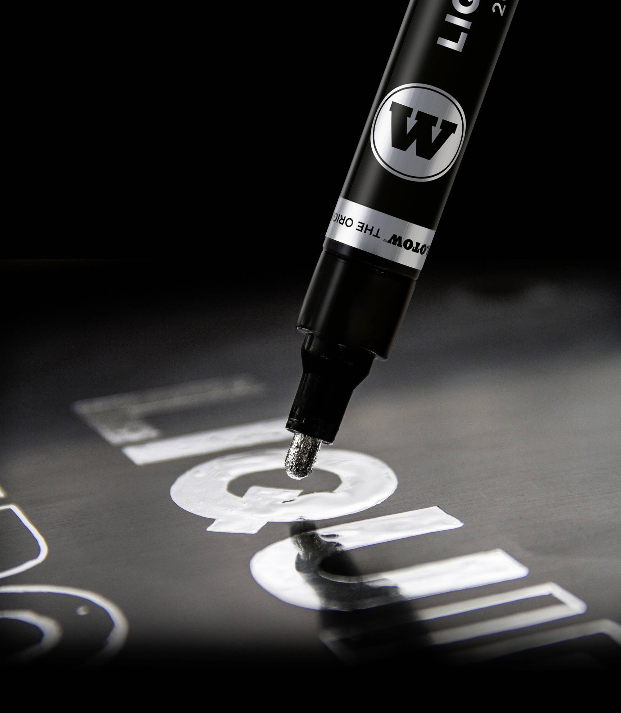 A black marker tip writes the word 'Liquid' in white letters on a dark surface.