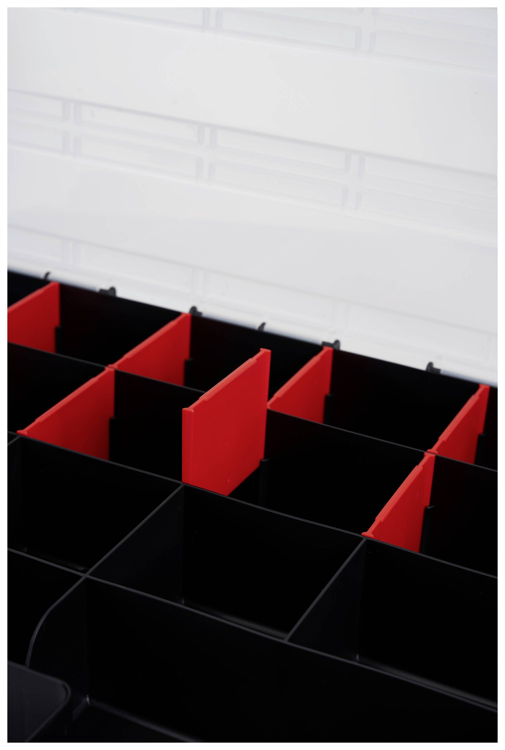 Black plastic box with red dividers creating separate compartments. A transparent surface in the background.