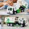 A child is playing with a toy rubbish lorry made of building blocks. The vehicle is marked with 'Recycling' and a green symbol.