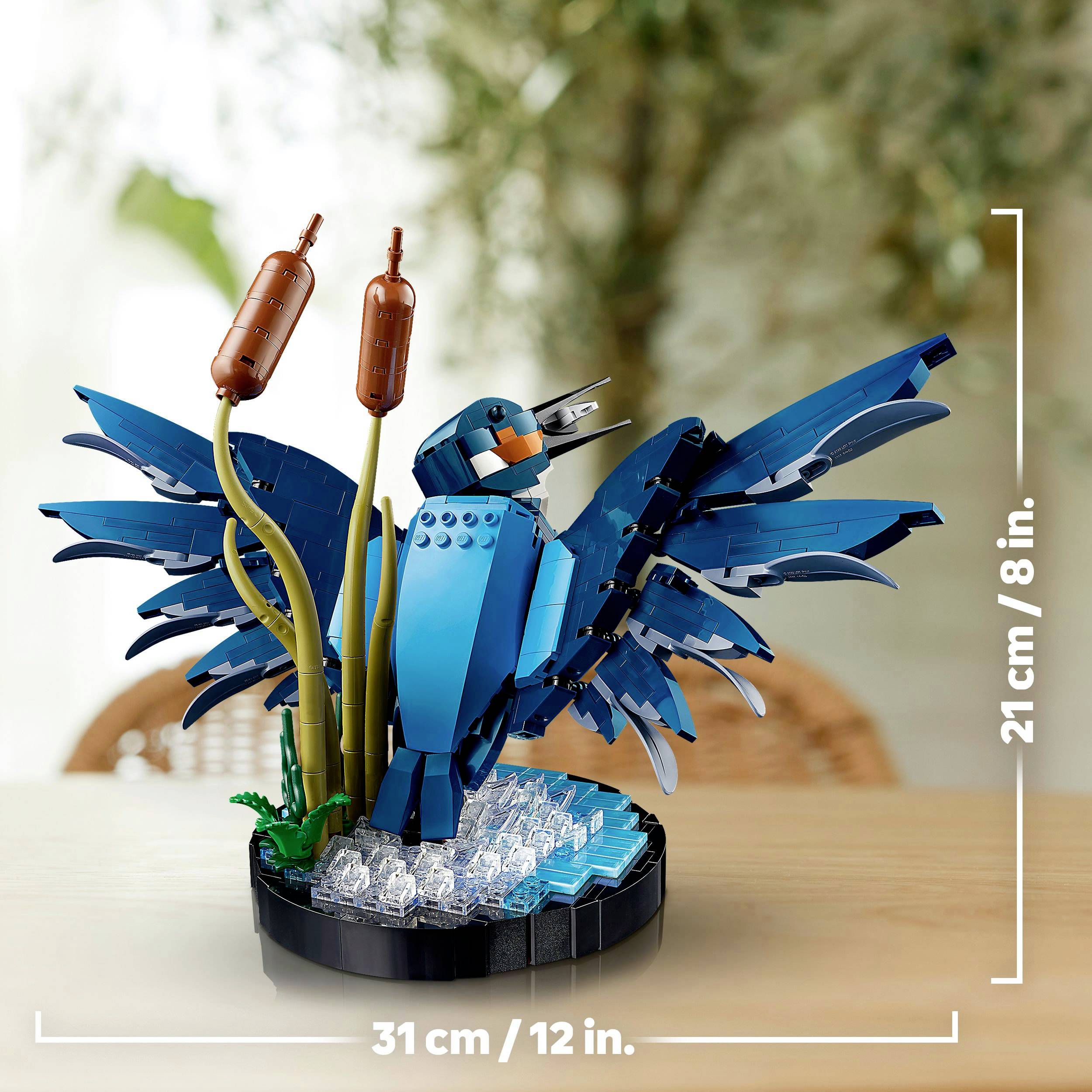 A bird model made of blue building blocks with outstretched wings, standing on a round base with reed stems.