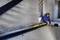 A person in workwear is using a spirit level to align a steel beam in an unfinished building. Wall and beams are visible in the background.