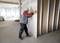 A person is checking the alignment of a plasterboard wall with a spirit level in an unfinished room.