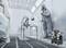 A worker in protective clothing is spray painting car parts in a spray booth. A spray gun and air compressor are visible.