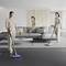Three people are synchronously hoovering a modern, minimalist room with a grey sofa and coffee table.