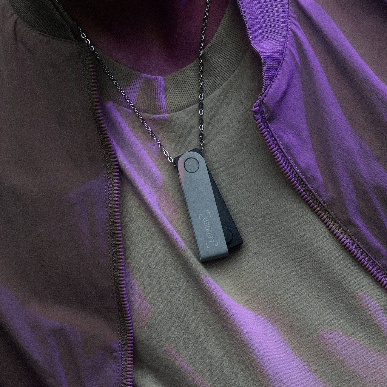 A person is wearing a metallic USB stick on a chain around their neck. The stick has a digital display and is used for data storage.