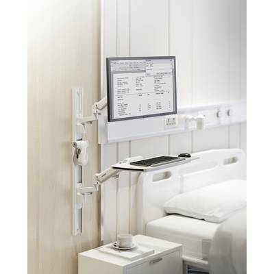 A screen with medical information is mounted on the wall next to a hospital bed. A keyboard is positioned underneath.