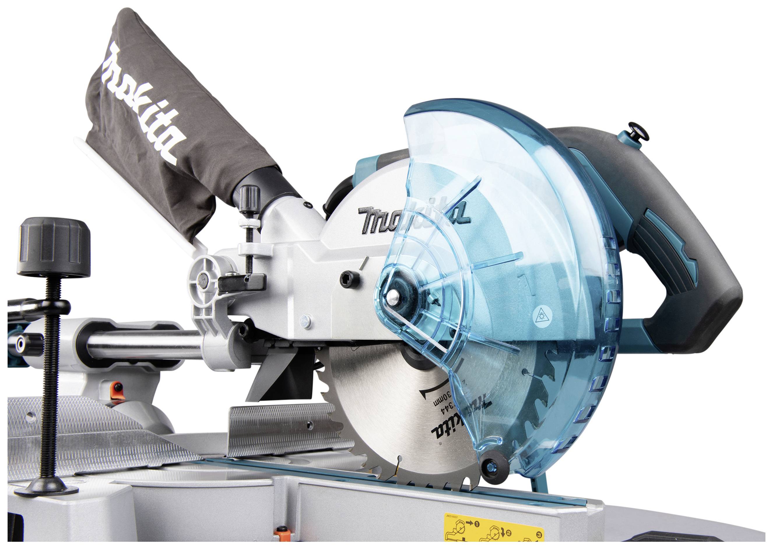 Mitre saw with blue protective shield and handle, with a black dust collection bag beside it; tool placed on a work surface.