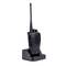 Black handheld radio sits on a charging station. It has a long antenna and side-mounted speaking and volume buttons.