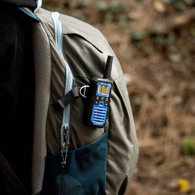 A person is wearing an outdoor jacket with a walkie-talkie in their pocket, presumably while hiking or during another outdoor activity.