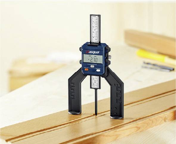 A digital depth gauge measures the thickness of a wooden board in a workshop environment. The display shows '2.70'.