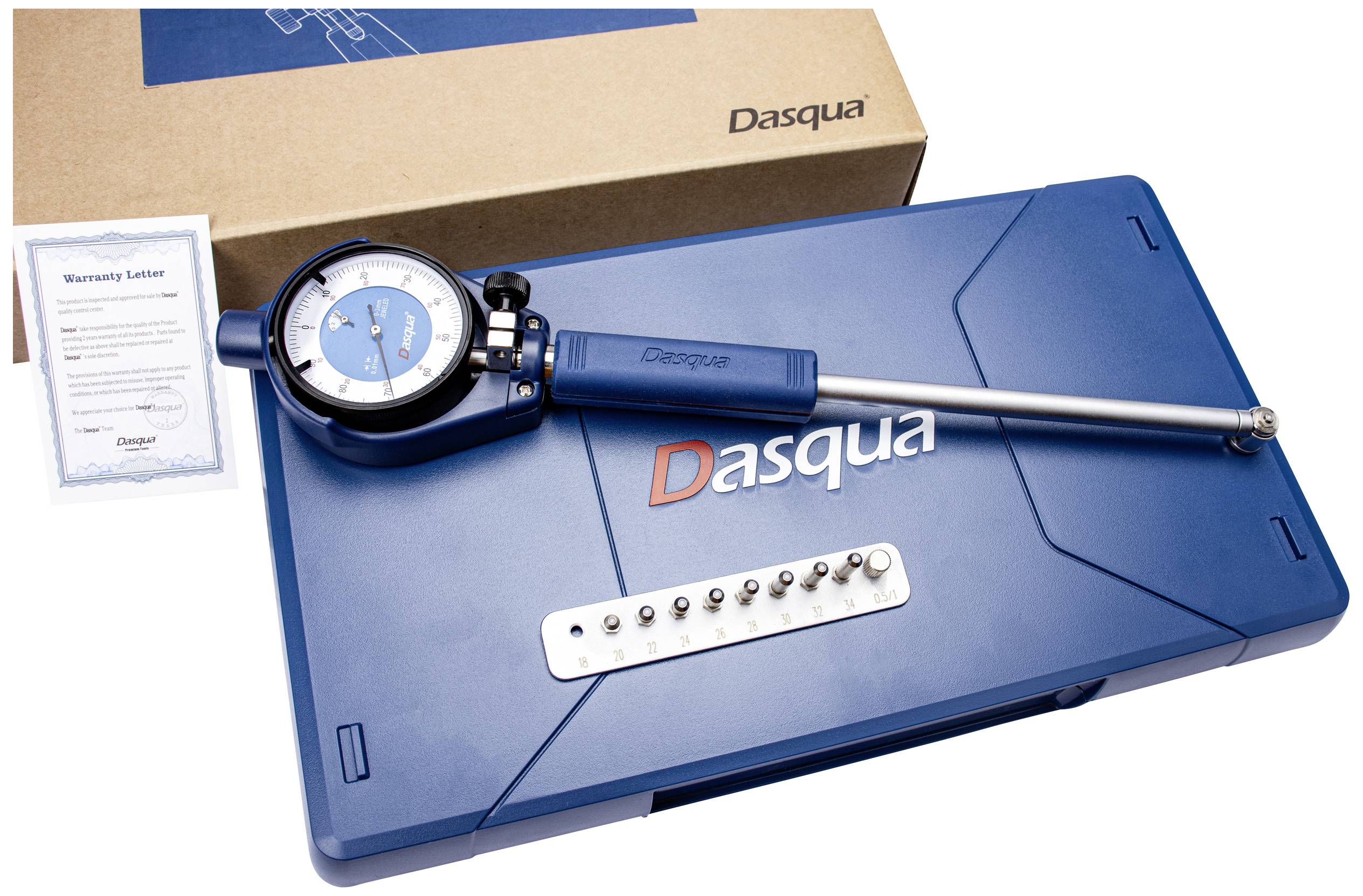 A blue measuring instrument with a dial and long metal rod lies on a blue case marked 'Dasqua'. Next to it is a guarantee certificate.